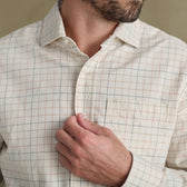 Man buttoning Tom Beckbe’s Prescott Estate Twill Shirt, a cream windowpane check—ideal for autumn style.