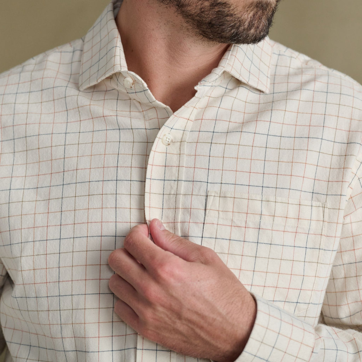 Man buttoning Tom Beckbe’s Prescott Estate Twill Shirt, a cream windowpane check—ideal for autumn style.