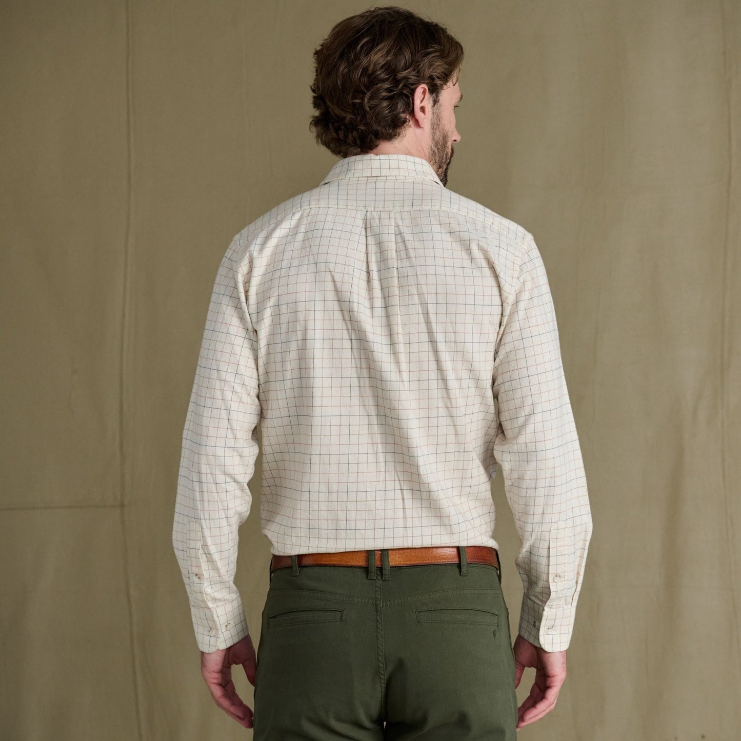 Man faces away wearing Tom Beckbe Prescott Estate Twill Shirt and green pants against a plain background.