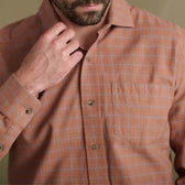 Man adjusts his collar in the Tom Beckbe Prescott Estate Twill Shirt—orange plaid, essential for your fall wardrobe.
