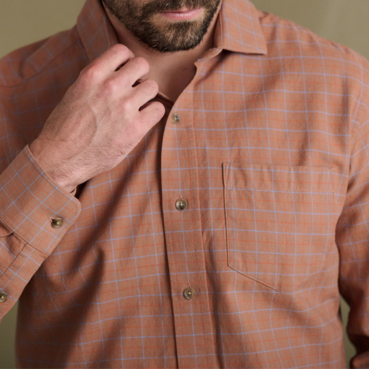 Man adjusts his collar in the Tom Beckbe Prescott Estate Twill Shirt—orange plaid, essential for your fall wardrobe.