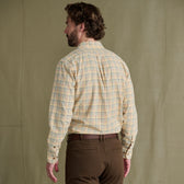 Man facing away wears a Tom Beckbe Prescott Estate Twill Shirt and brown pants, in front of a beige background.