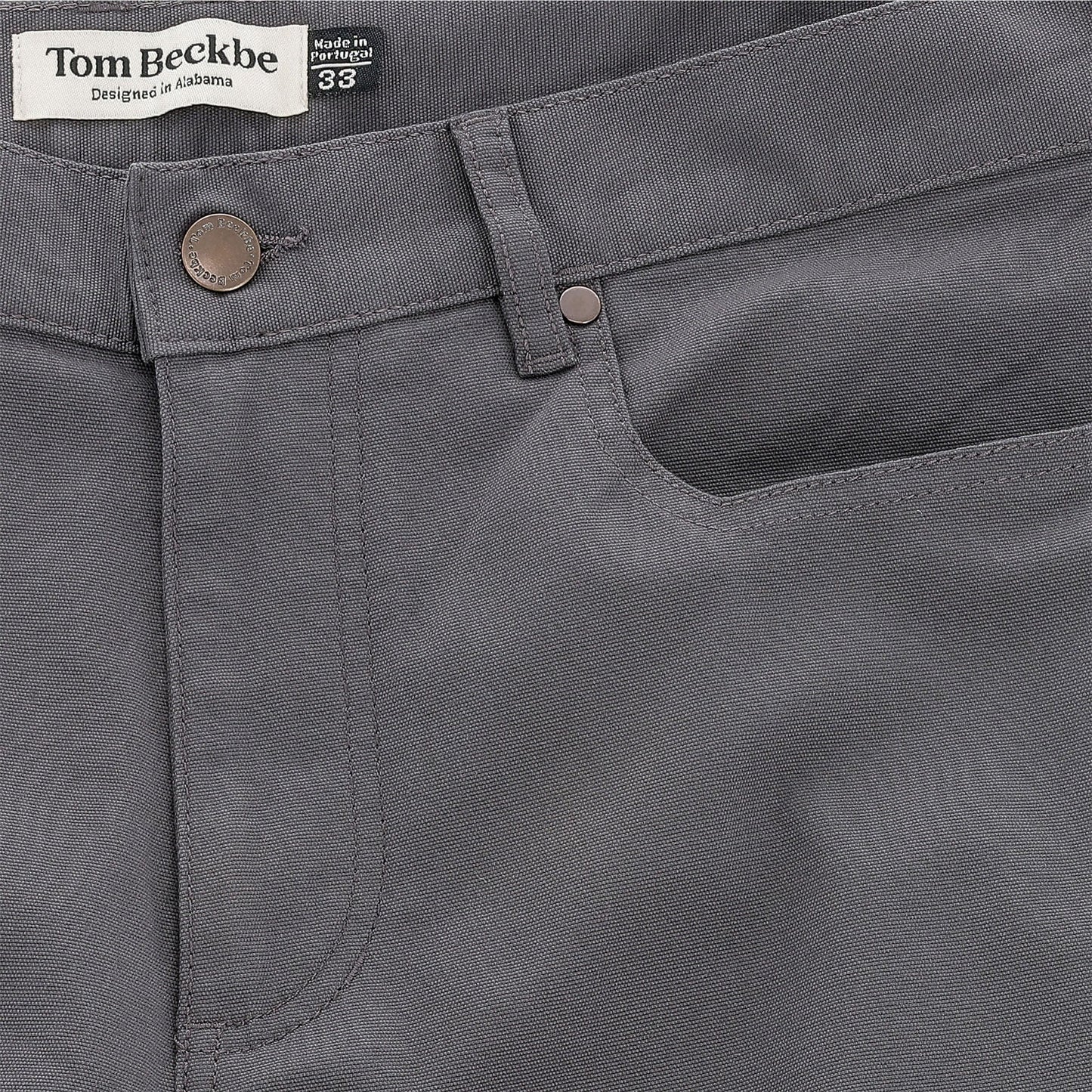 Close-up of Tom Beckbe Reid Straight Leg Cotton Chino Pant in gray with button, front pocket, and logo waistband label.