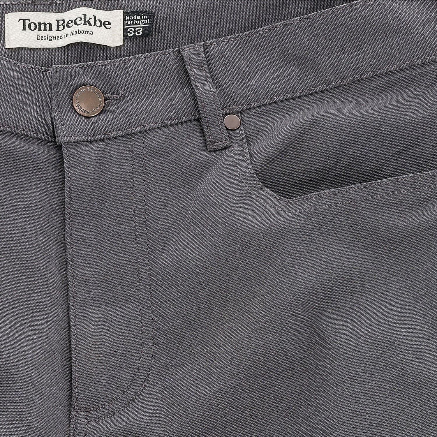 Close-up of Tom Beckbe Reid Straight Leg Cotton Chino Pant in gray with button, front pocket, and logo waistband label.