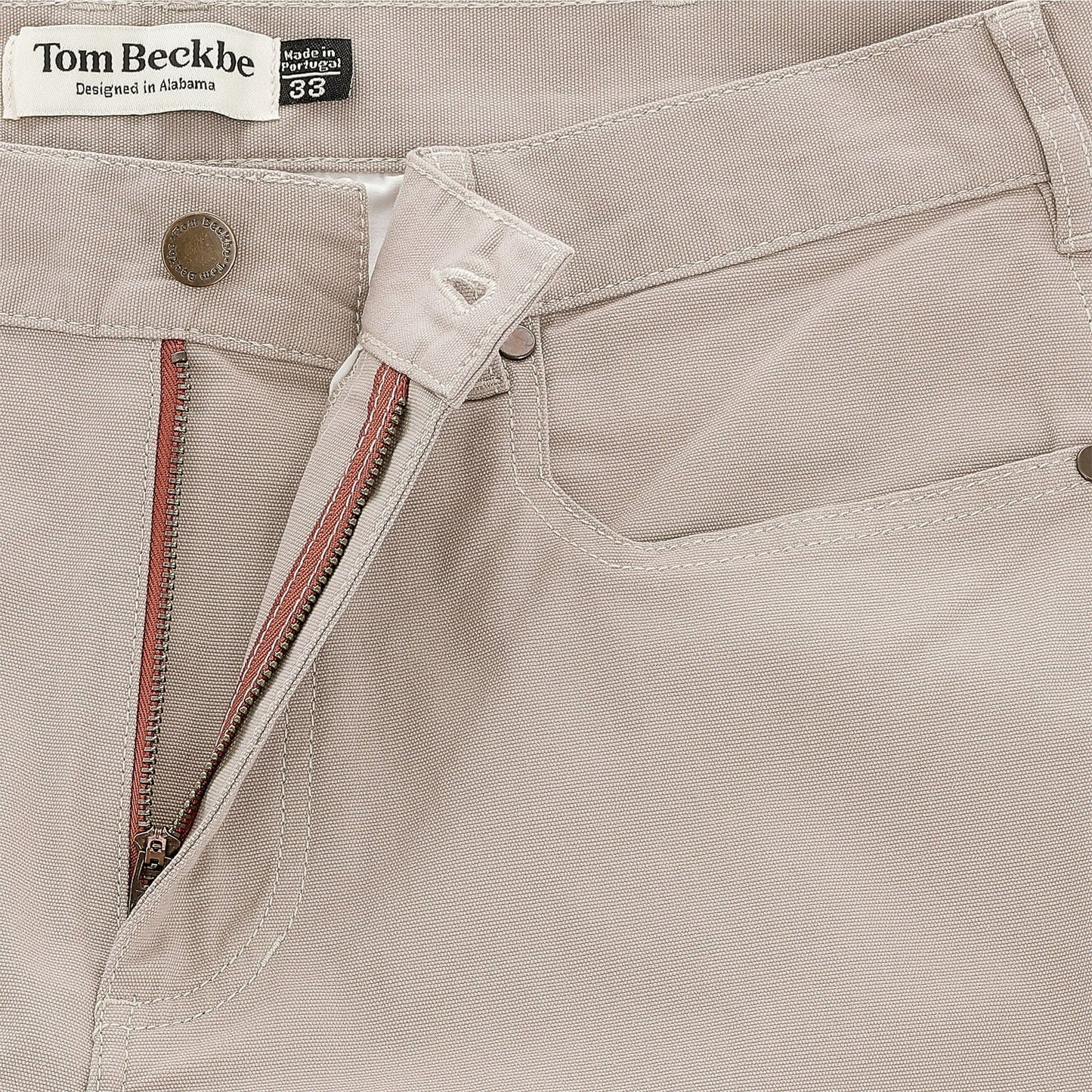 Close-up of Tom Beckbe Reid Straight Leg Cotton Chino Pant in beige, showing button, zipper, and waistband label.