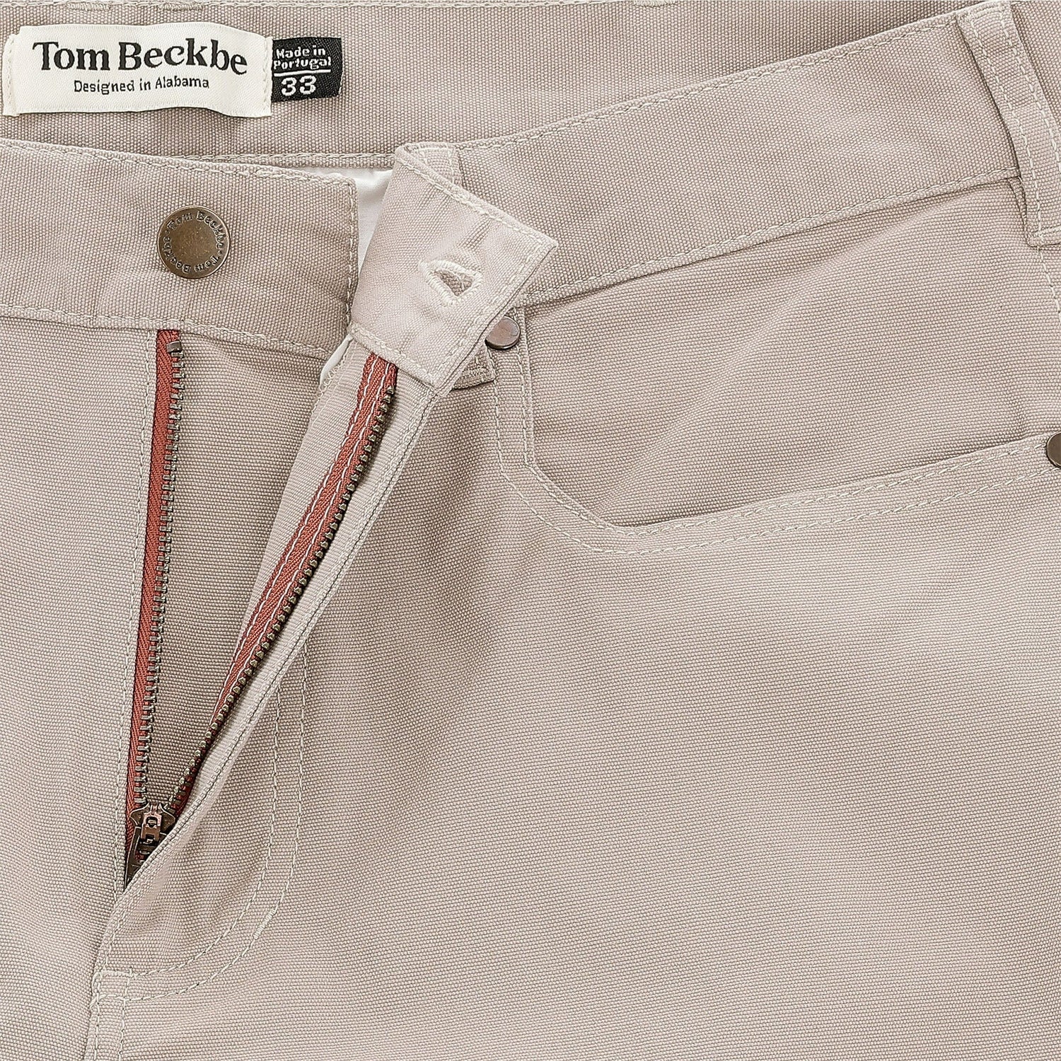 Close-up of Tom Beckbe Reid Straight Leg Cotton Chino Pant in beige, showing button, zipper, and waistband label.