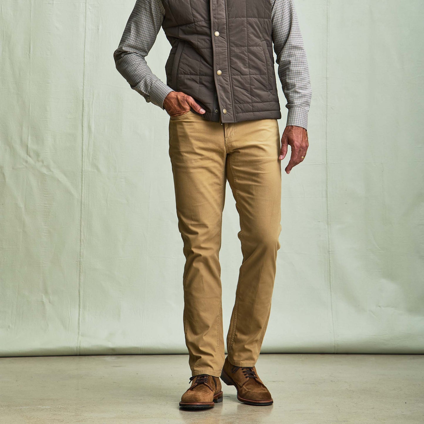 A man in a brown vest and checkered shirt wears Tom Beckbe Reid Straight Leg Cotton Chino Pants against a light backdrop.