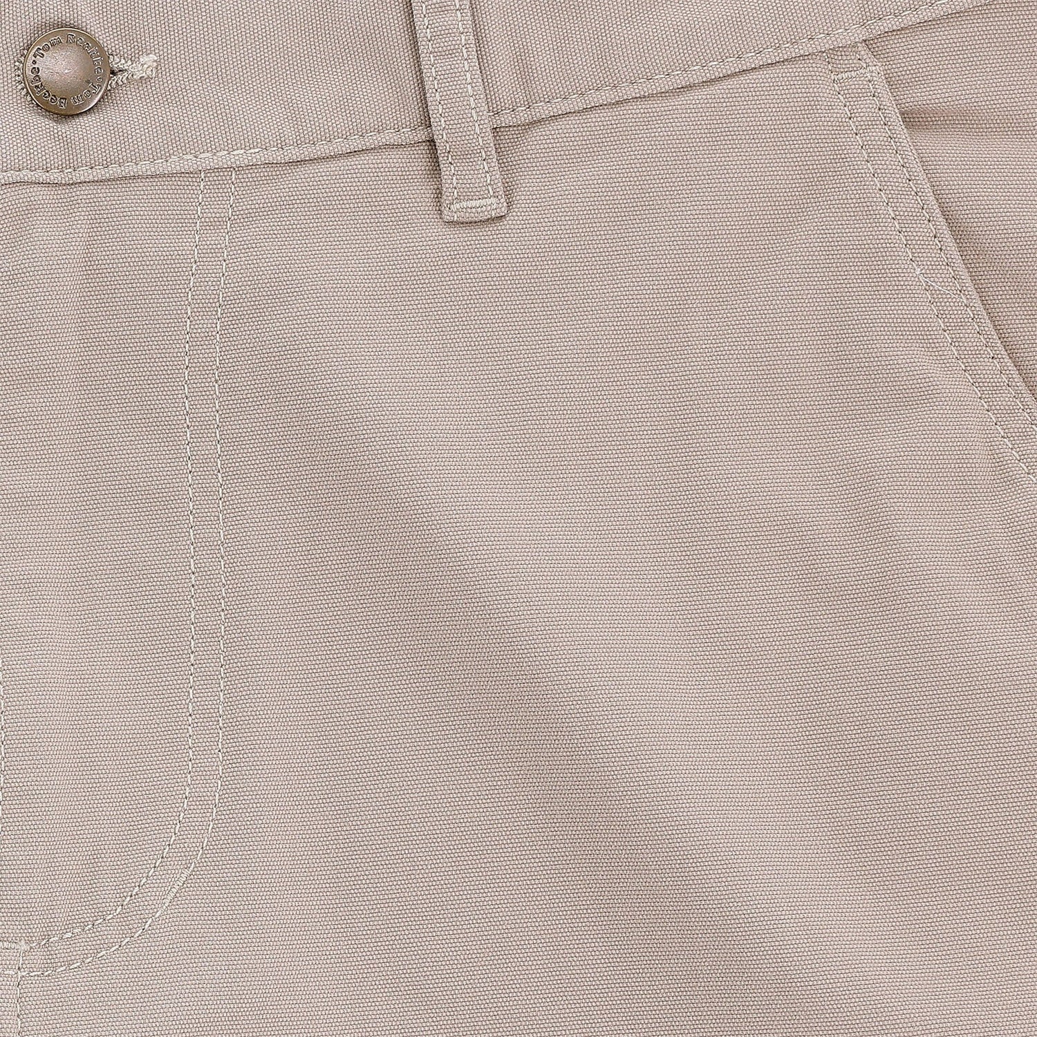 Close-up of Tom Beckbe Reid Short, light beige, mid-rise with button, belt loop, seam details, and antique brass zip fly.