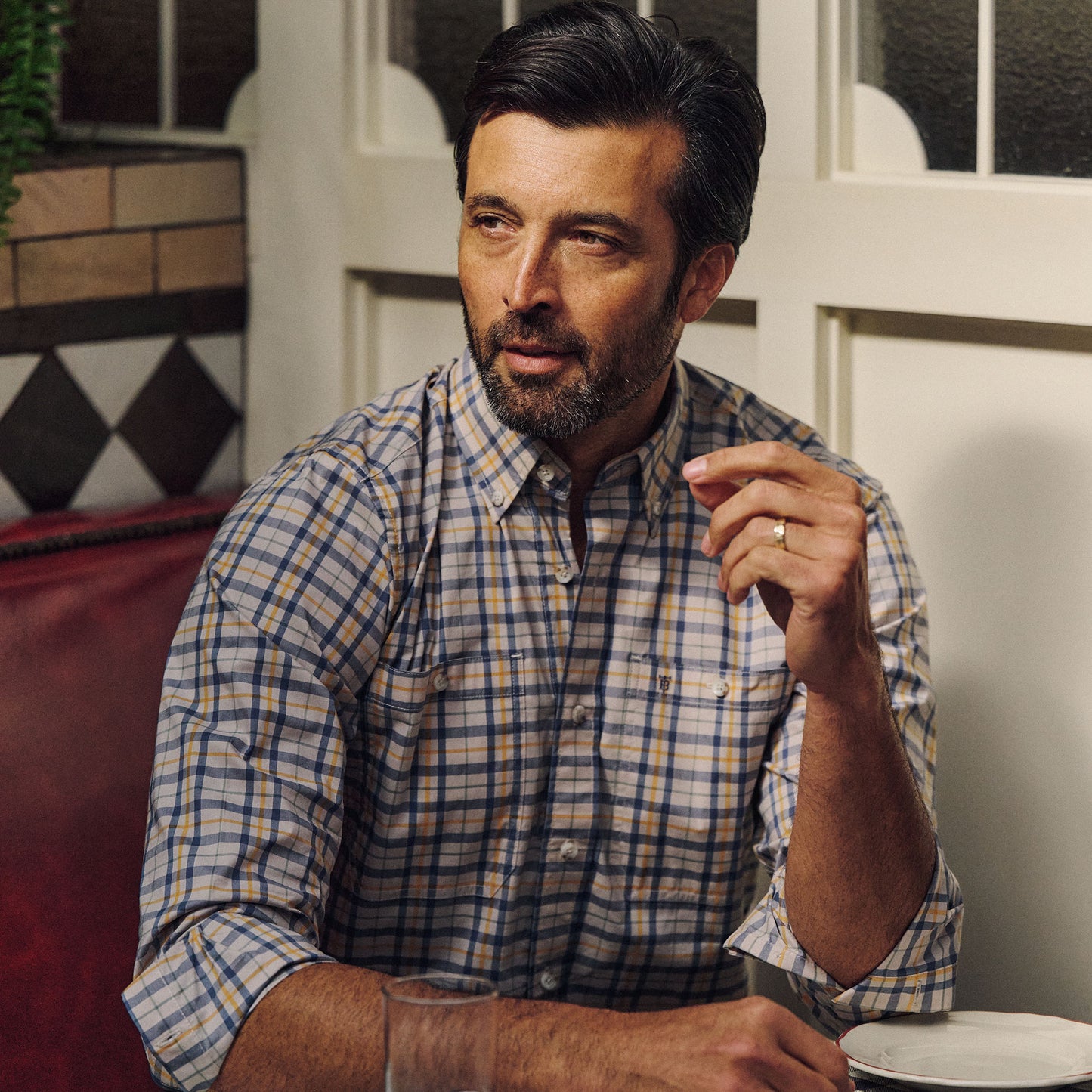 A bearded man with dark hair sits at a table, wearing the Tom Beckbe Tidewater Shirt and holding a cigarette.