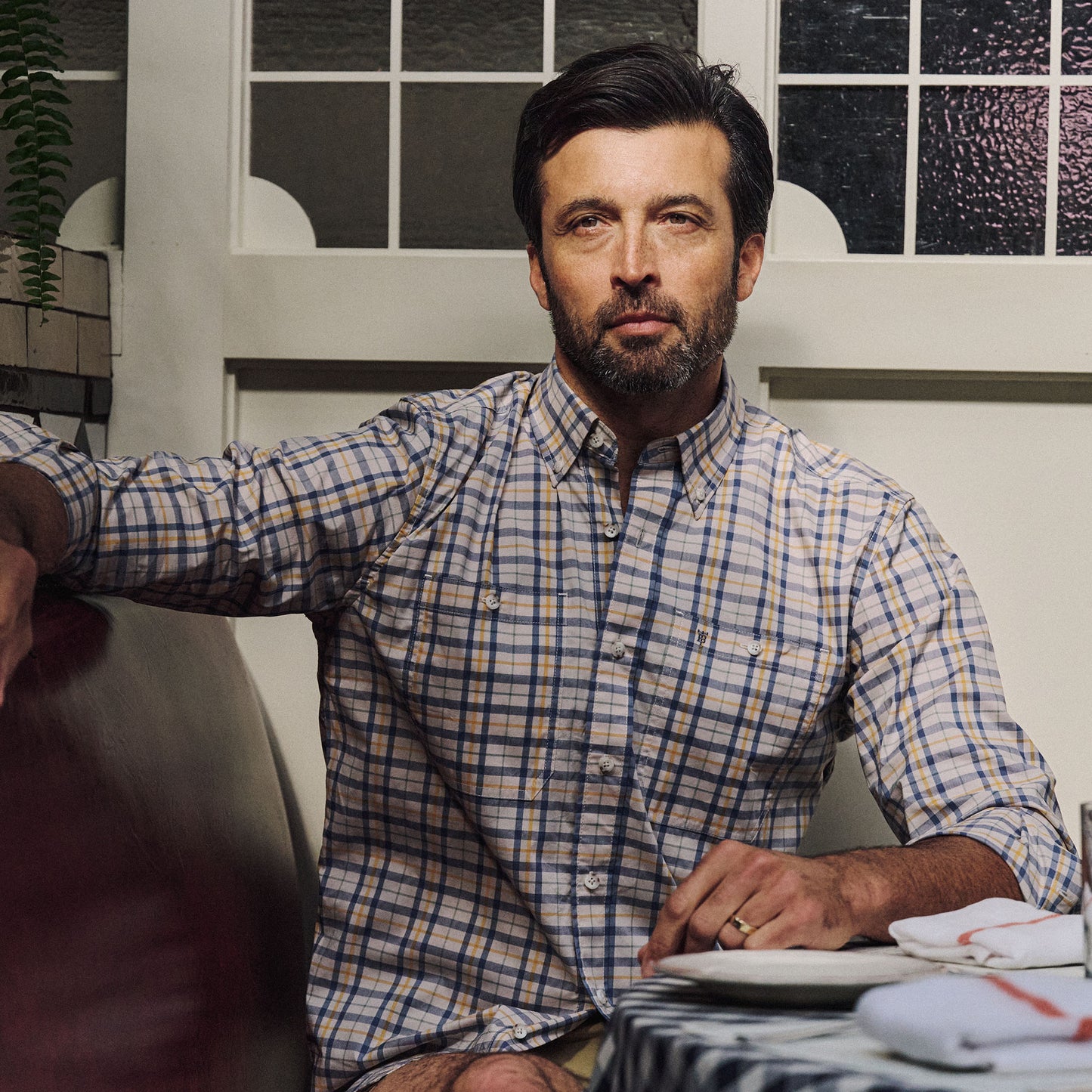 A bearded man in a Tom Beckbe Tidewater Shirt (UPF 30+) sits at a table, looking at the camera.