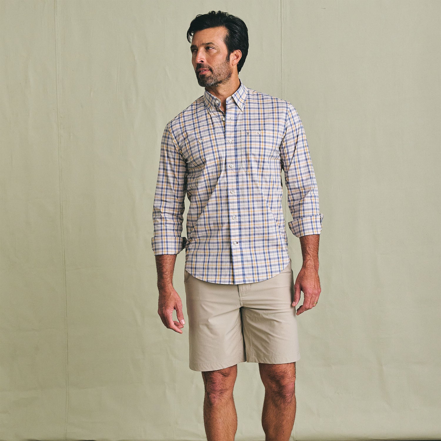 Man in a Tom Beckbe Tidewater Shirt and beige shorts stands against a plain light-colored background.