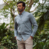 Man in a greenhouse wearing the Tom Beckbe Tidewater Shirt and beige pants, hands in his pockets.