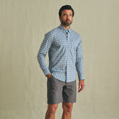 A man stands against a plain background wearing the Tom Beckbe Tidewater Shirt and gray shorts.