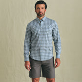 A man wears the Tom Beckbe Tidewater Shirt and gray shorts, standing against a plain beige background.