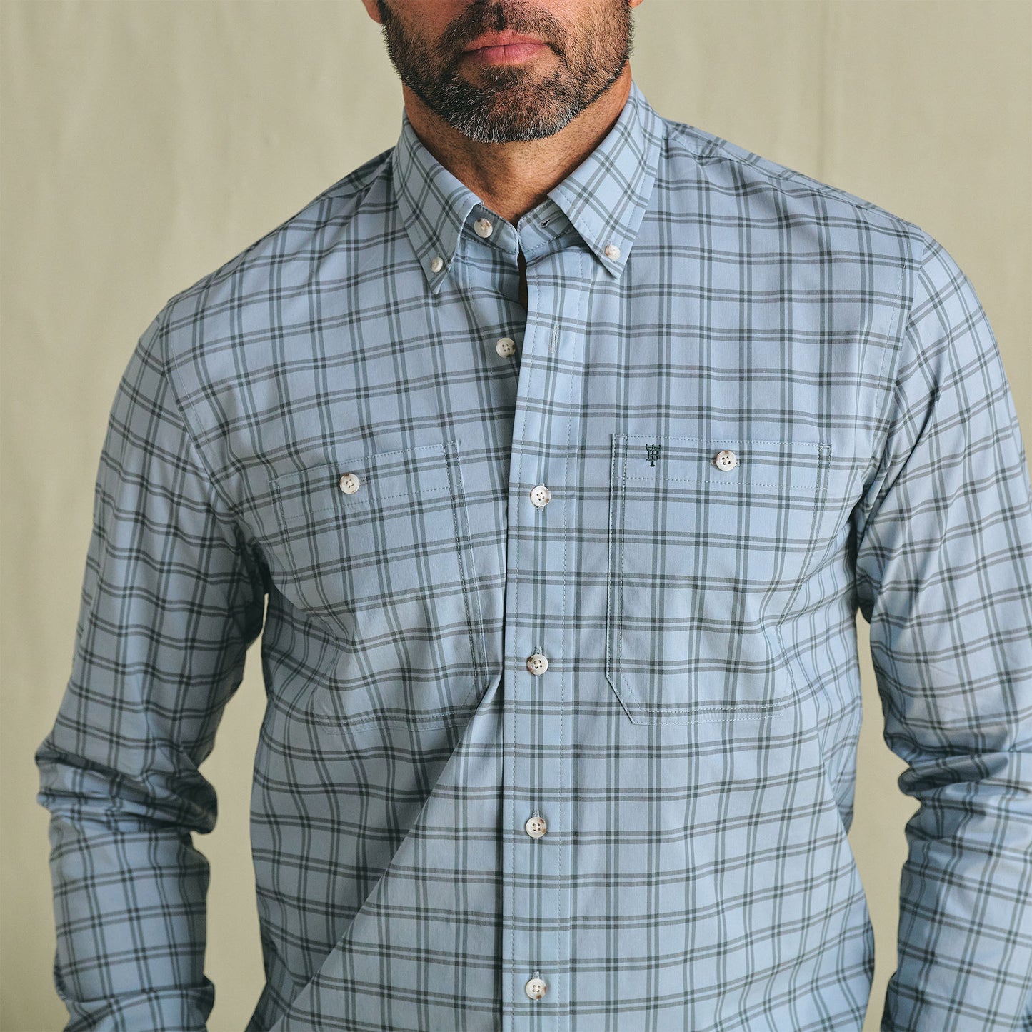 Man wears Tom Beckbe Tidewater Shirt, light blue plaid with UPF 30+ and two chest pockets, against plain background.
