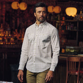 Man wears the Tom Beckbe Tidewater Shirt indoors, standing among wooden furniture in a dimly lit room.