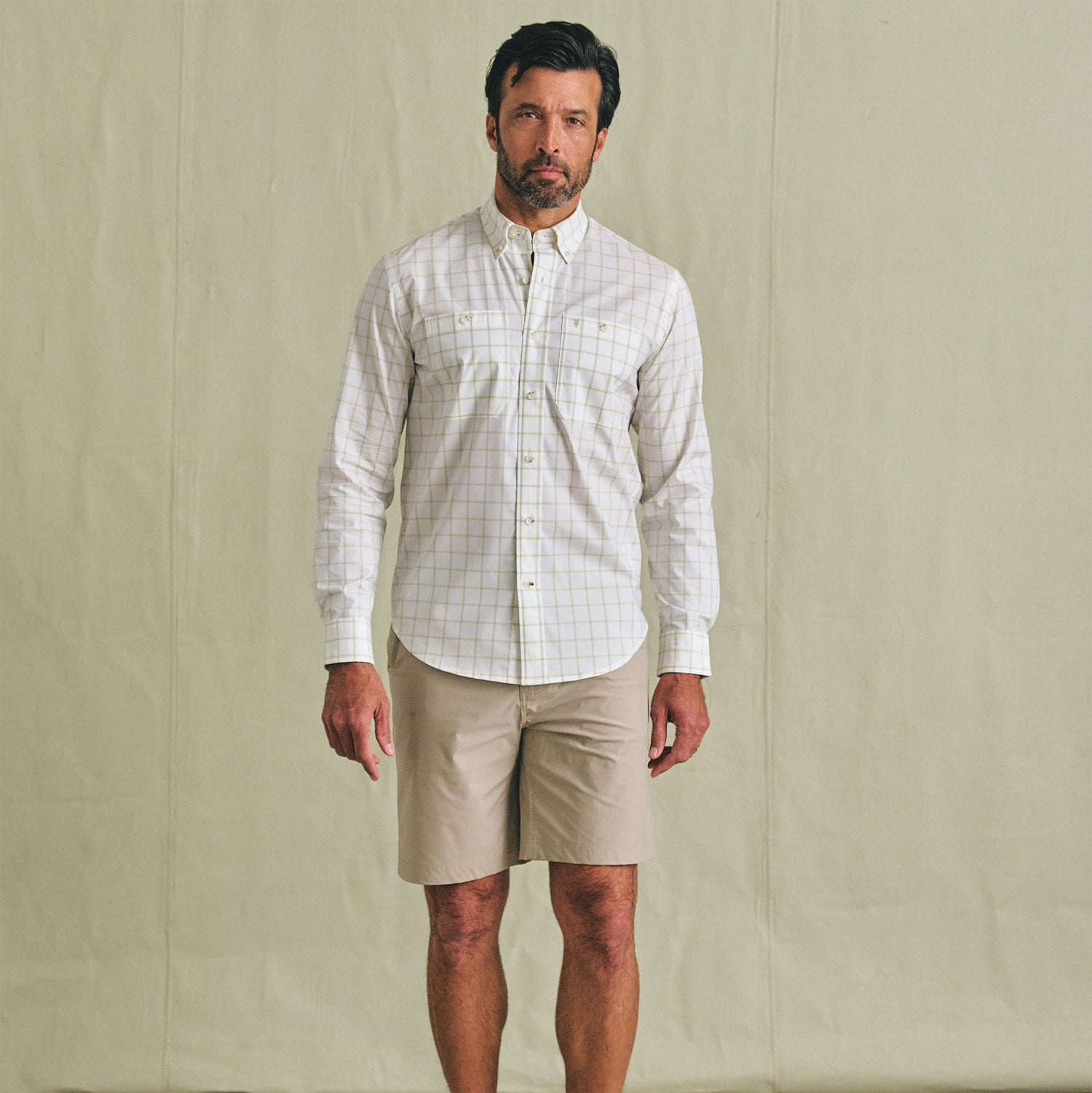 Man facing forward in a Tom Beckbe Tidewater Shirt, UPF 30+, and beige shorts against a plain backdrop.