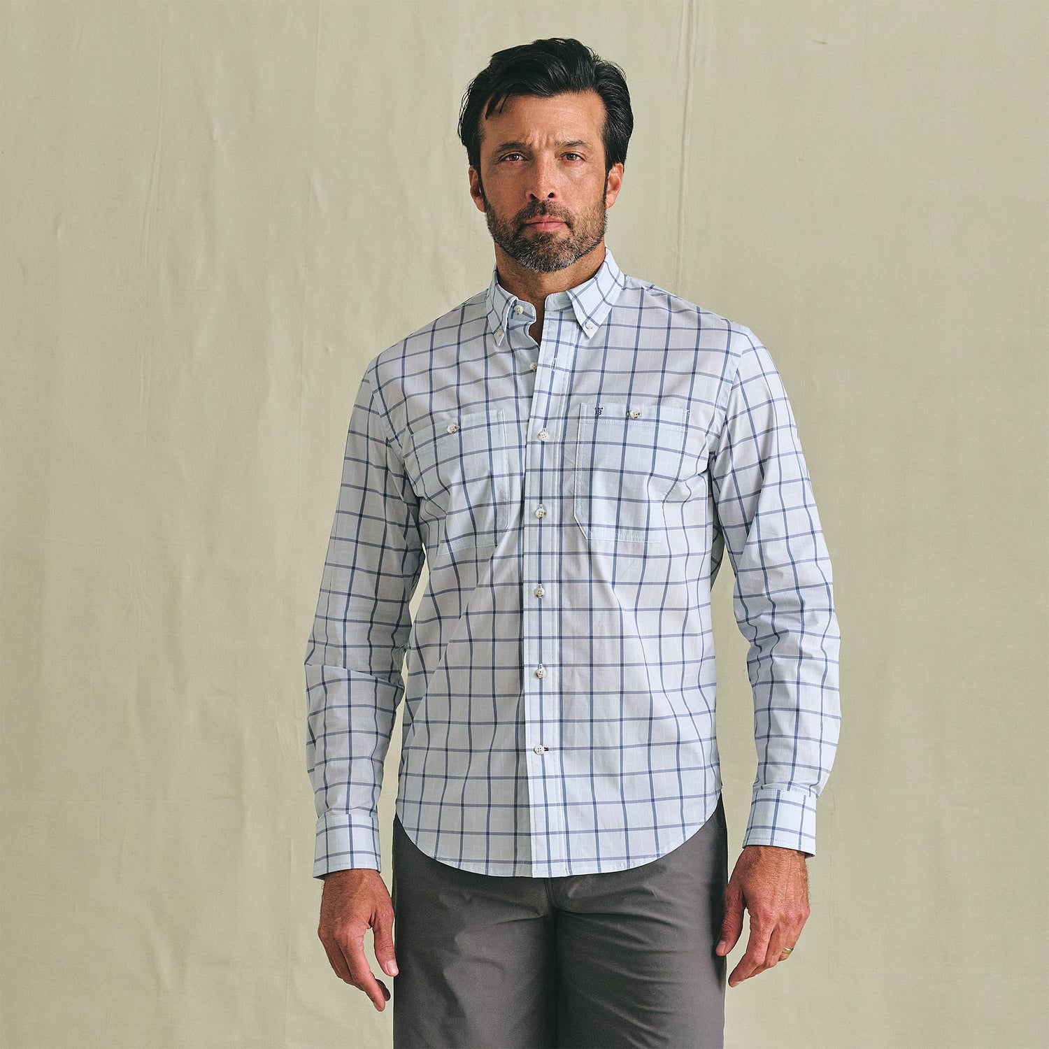 Man wearing the Tom Beckbe Tidewater Shirt with blue checks and gray pants, standing against a plain background.