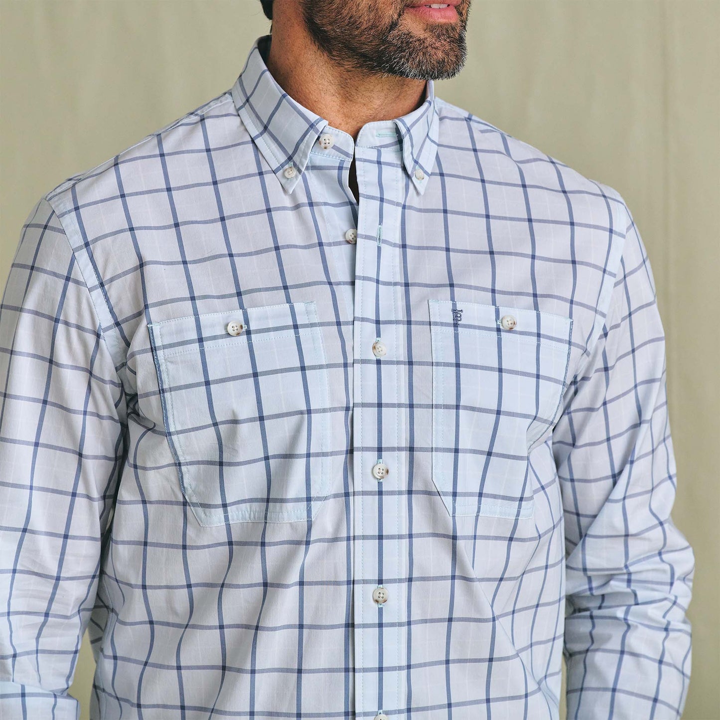 Man wearing the Tom Beckbe Tidewater Shirt, a light blue plaid long sleeve with two chest pockets, shown shoulders to waist.