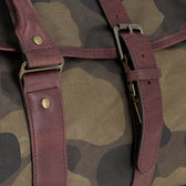 Close-up of Tom Beckbe's Classic Camo Weekender Duffel Bag with brown leather straps and metal buckles.