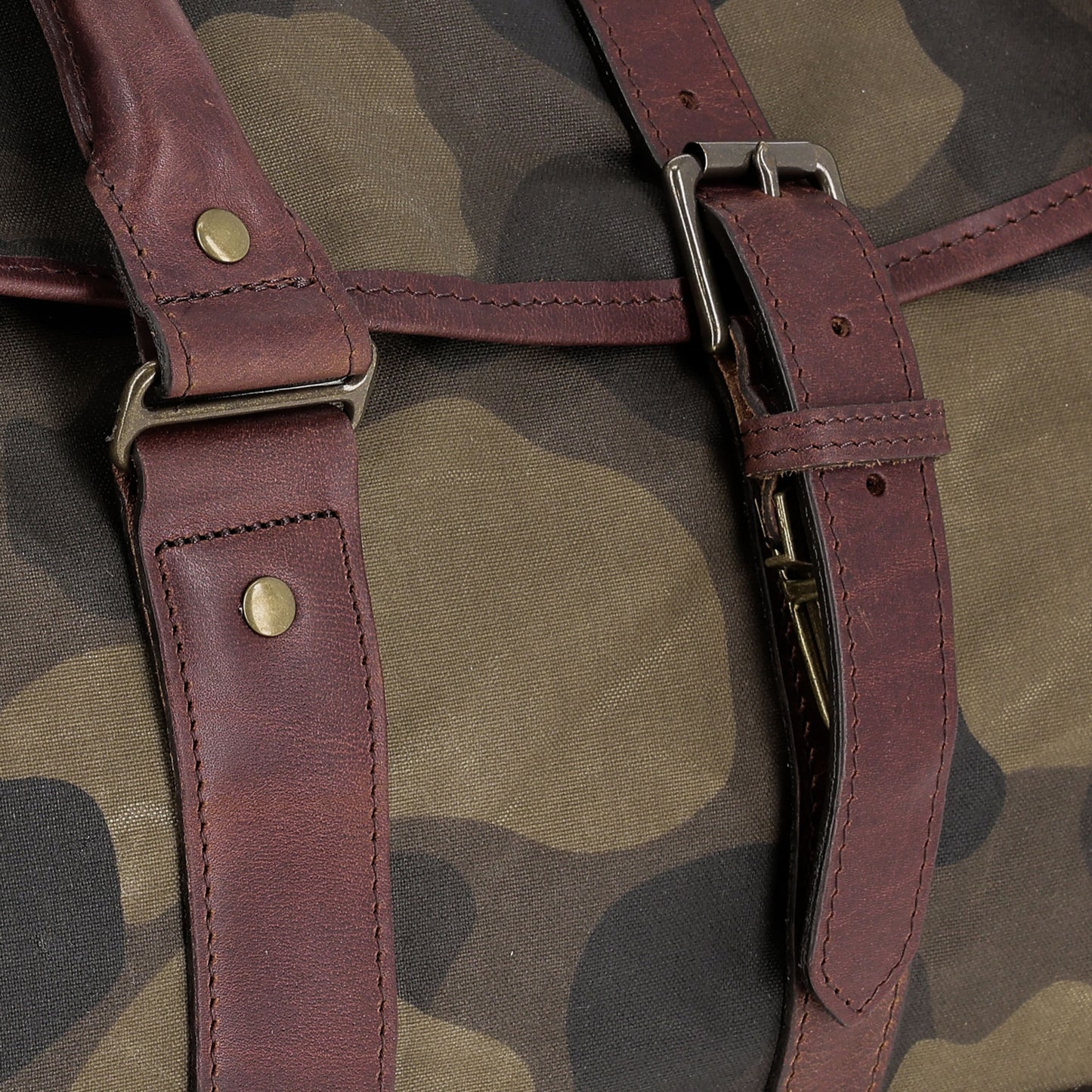 Close-up of Tom Beckbe's Classic Camo Weekender Duffel Bag with brown leather straps and metal buckles.