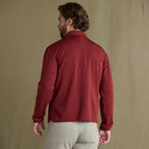 Man with light brown hair wears the Tom Beckbe Tucker Fleece Quarter Zip and beige pants, back facing the camera.