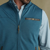 Man wearing Tom Beckbe Tucker Fleece Vest, teal zip-up over blue plaid shirt, shown neck to waist.