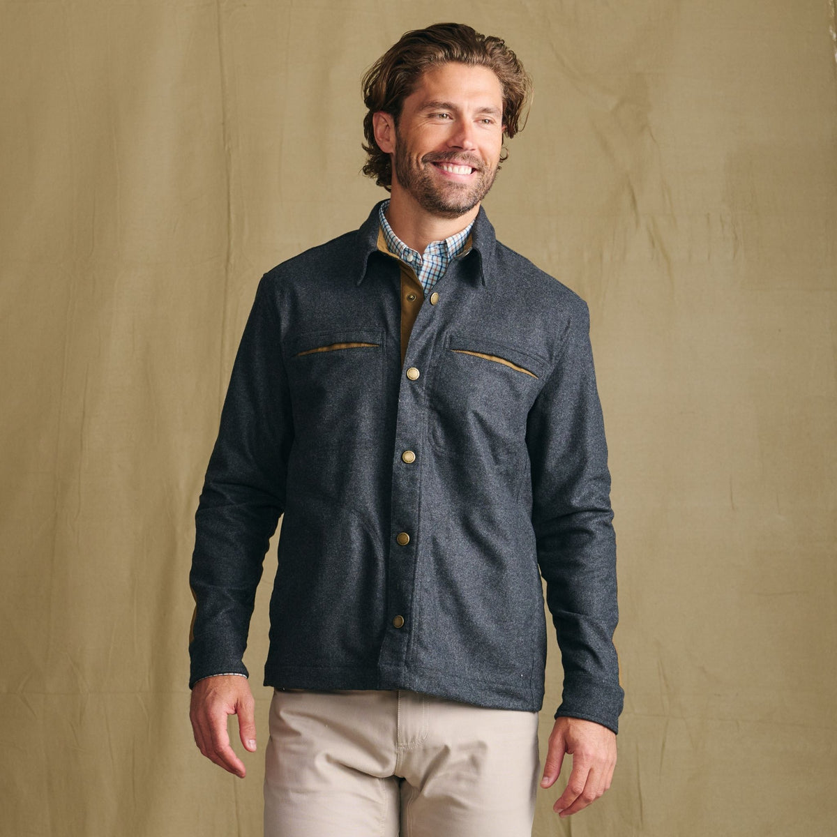 Man smiling in a Tom Beckbe Westport Wool Overshirt, collared shirt, and tan pants against a plain background.