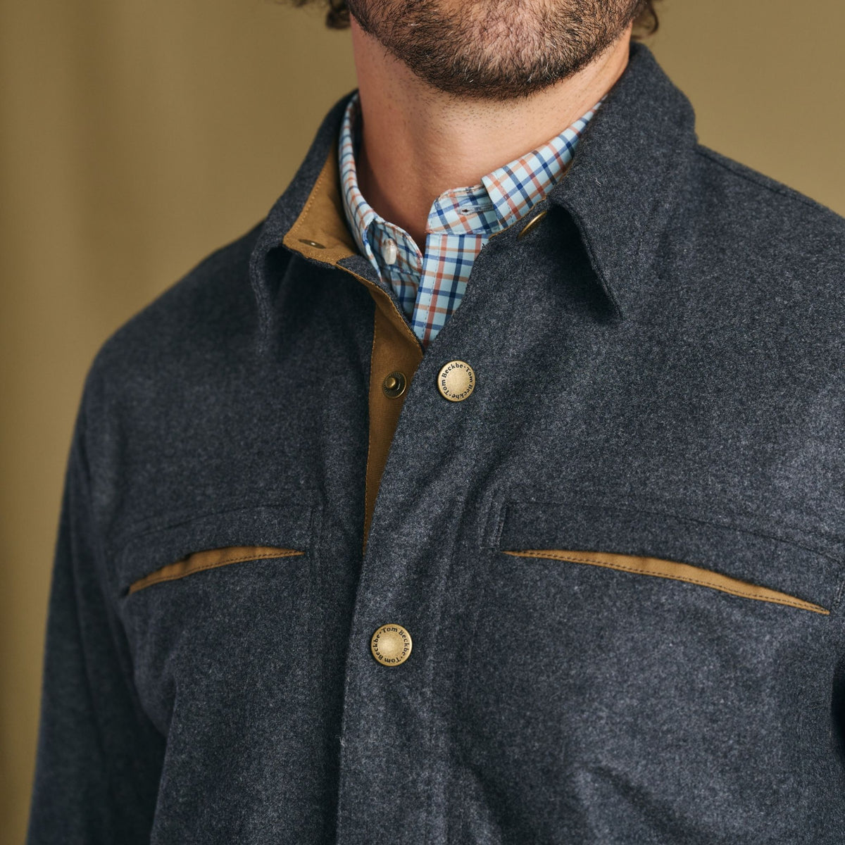 Man wearing Tom Beckbe Westport Wool Overshirt with tan accents over blue-orange plaid shirt, shown shoulders up.