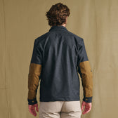 A man faces away in a Tom Beckbe Westport Wool Overshirt with tan elbow patches, set against a plain backdrop.