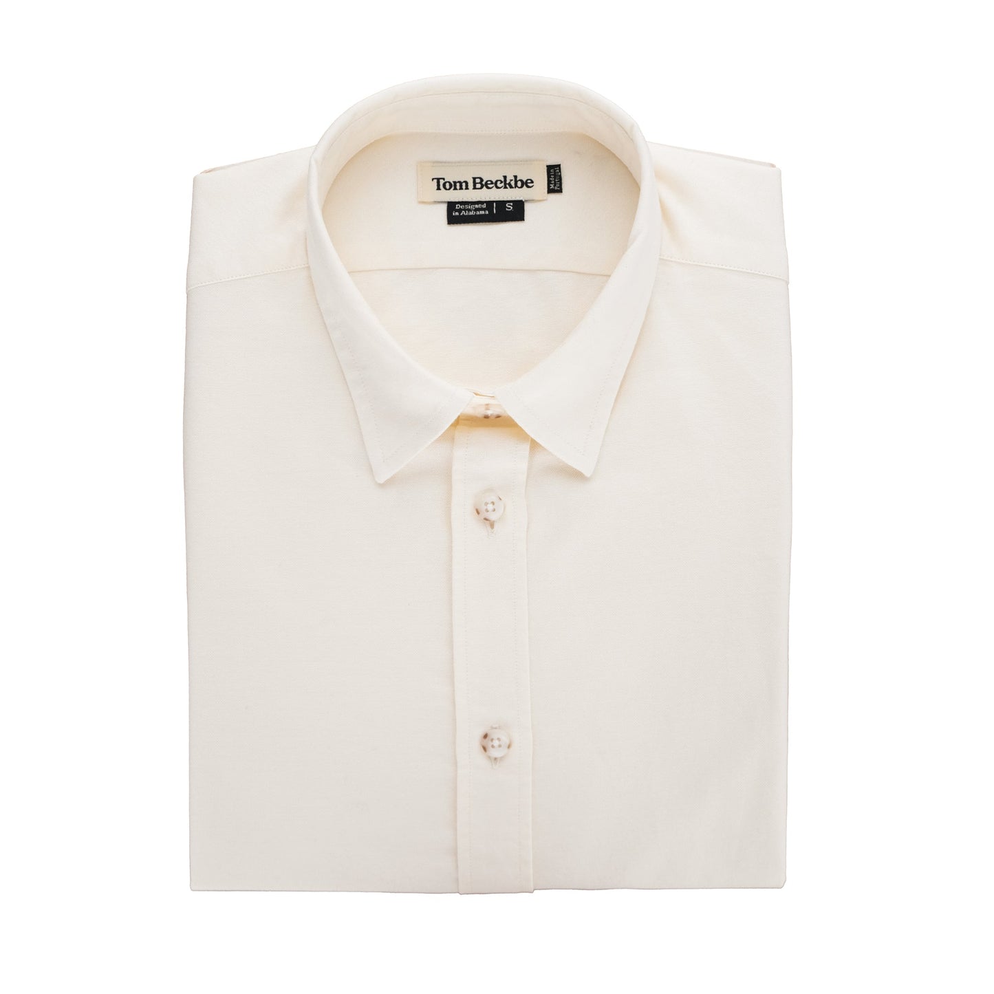 A folded beige Womens Oxford Shirt by Tom Beckbe with buttons and brand label on the collar against a plain background.