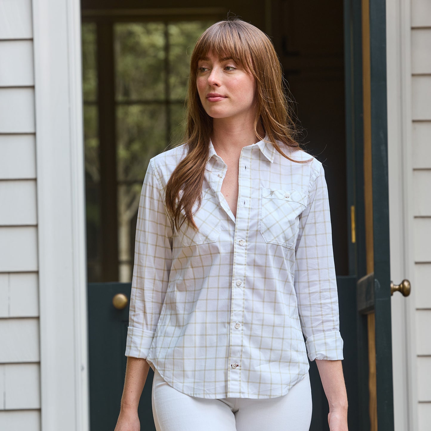 A woman in a Tom Beckbe Women's Tidewater Shirt with UPF 30+ stands in a doorway, wearing a neutral expression.