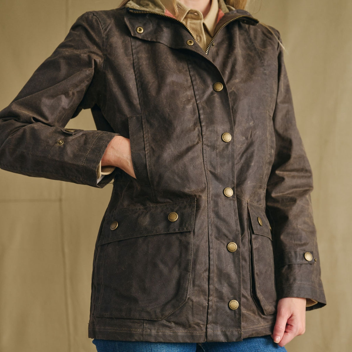 Woman in Tom Beckbe’s Blakeley Jacket—weatherproof cotton with snap buttons and large pockets, against a plain background.