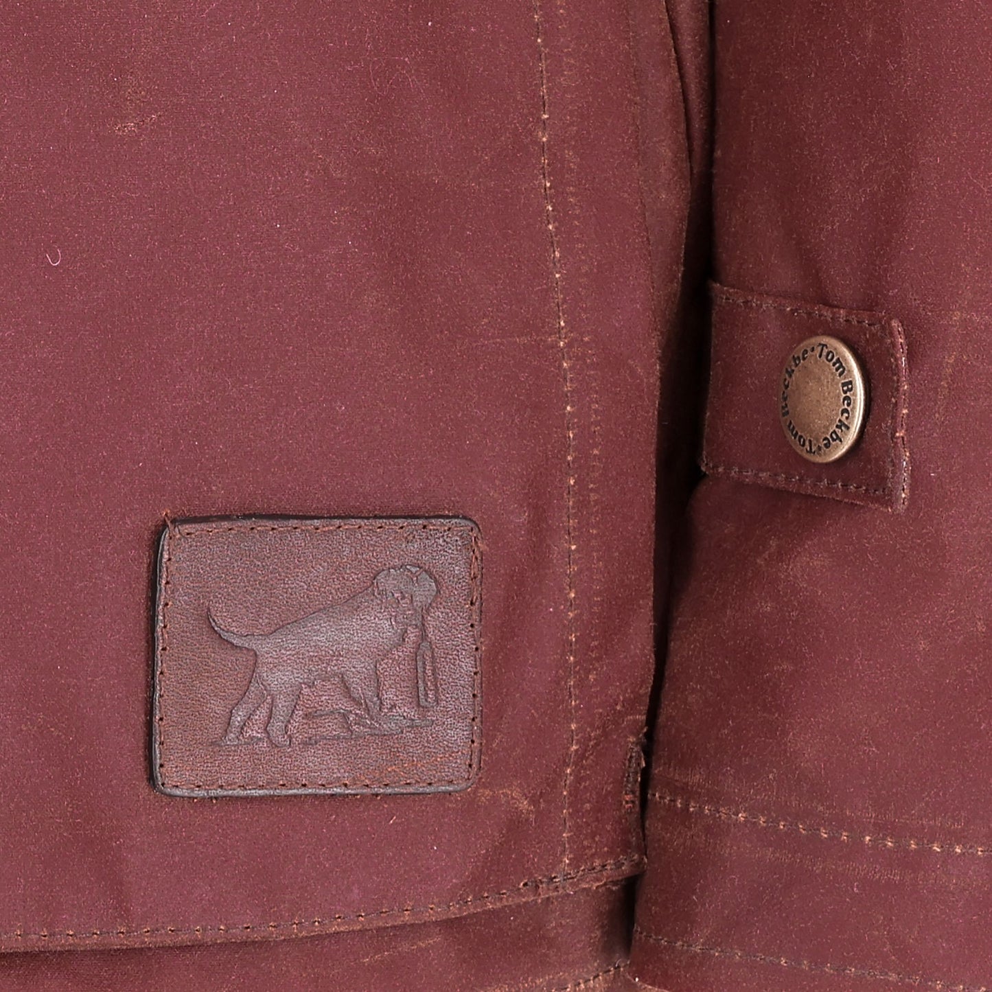 Close-up of the Women's Fox Red Blakeley Jacket by Tom Beckbe, featuring waxed cotton and a dog leather patch.