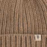 Close-up of the Tom Beckbe Wool Cap, a ribbed brown lambswool beanie with folded brim and small white monogram tag.
