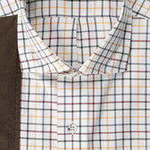 Close-up of Tom Beckbe’s Carrington Shooting Shirt in plaid—white, yellow, red, green—beside brown fabric.