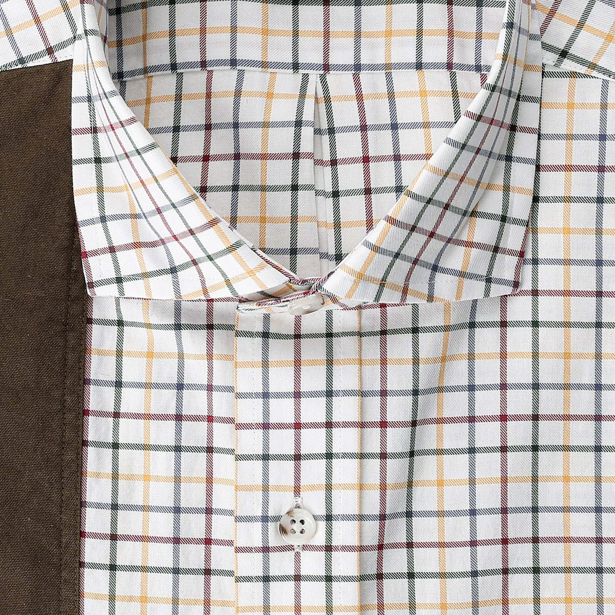 Close-up of Tom Beckbe’s Carrington Shooting Shirt in plaid—white, yellow, red, green—beside brown fabric.
