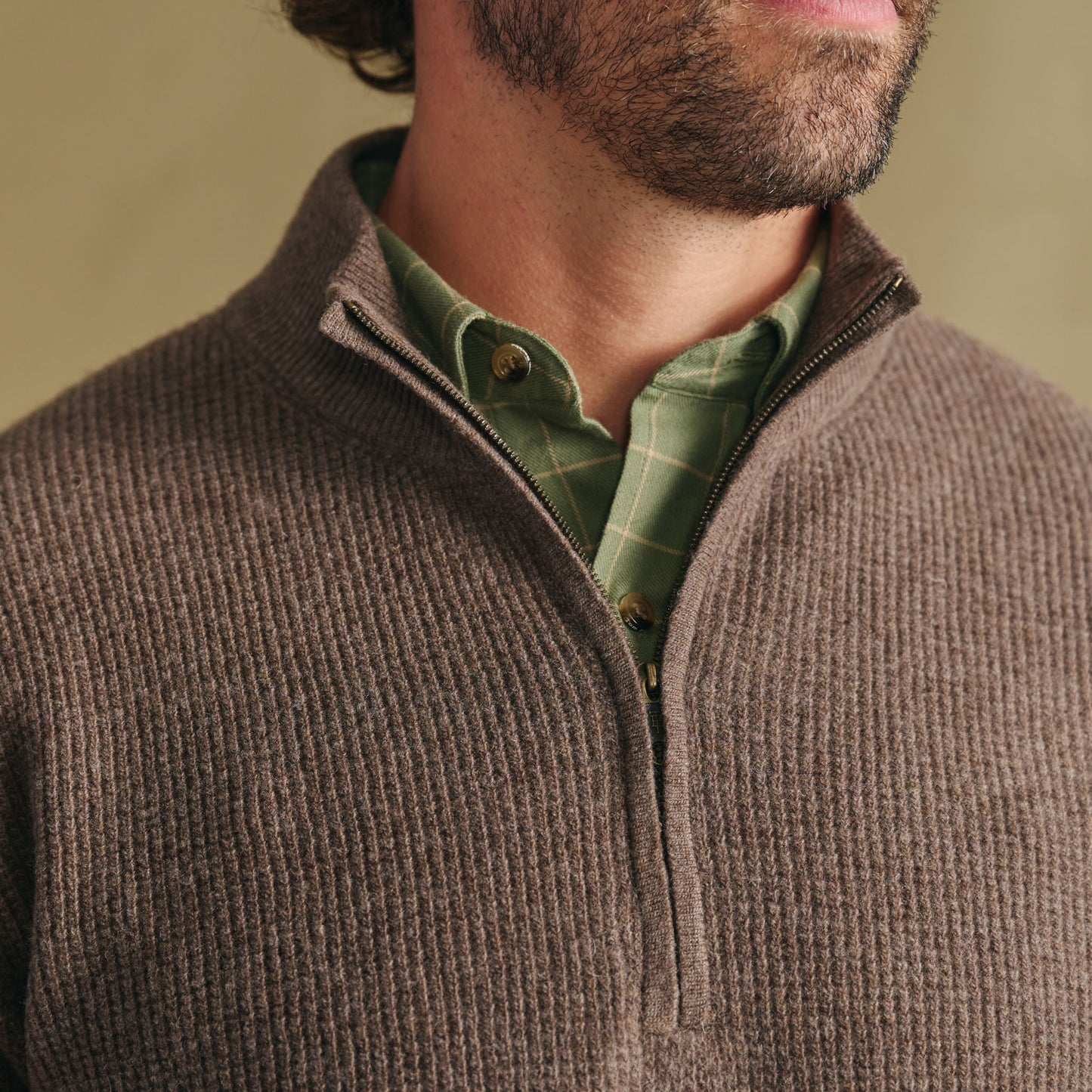 Man wearing Tom Beckbe Farris Waffle Knit Quarter Zip over a green plaid shirt; neck to chest view, partial face.