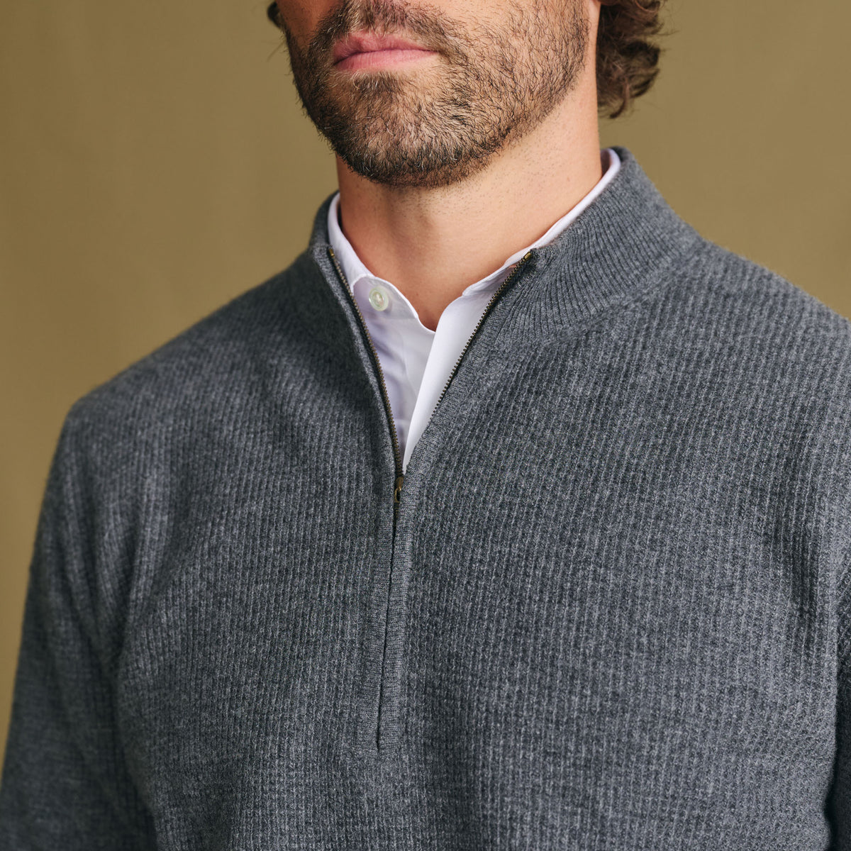 Man wears Tom Beckbe Farris Waffle Knit Quarter Zip over a white shirt, shown shoulders to chin, plain background.