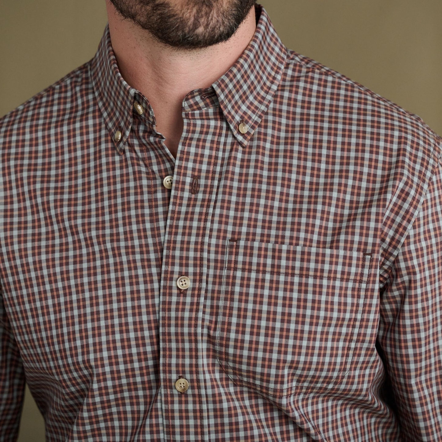Man in Tom Beckbe Powell Performance Shirt, brown/white/blue plaid, shown shoulders to mid-chest.