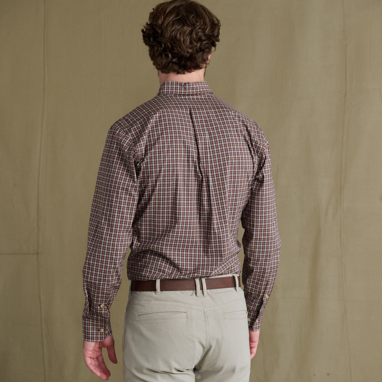 Man models the Tom Beckbe Powell Performance Shirt, facing away in light pants against a plain backdrop.