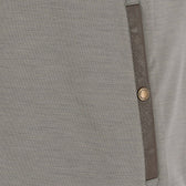 Close-up of a gray fabric garment with a brown vertical trim and a single round metallic button.