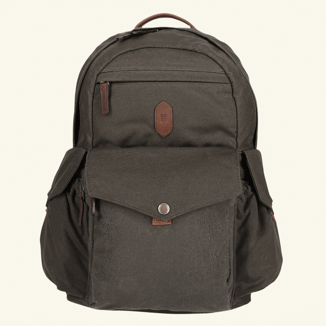A brown backpack with multiple pockets and a top handle, featuring leather accents and a front snap pocket.