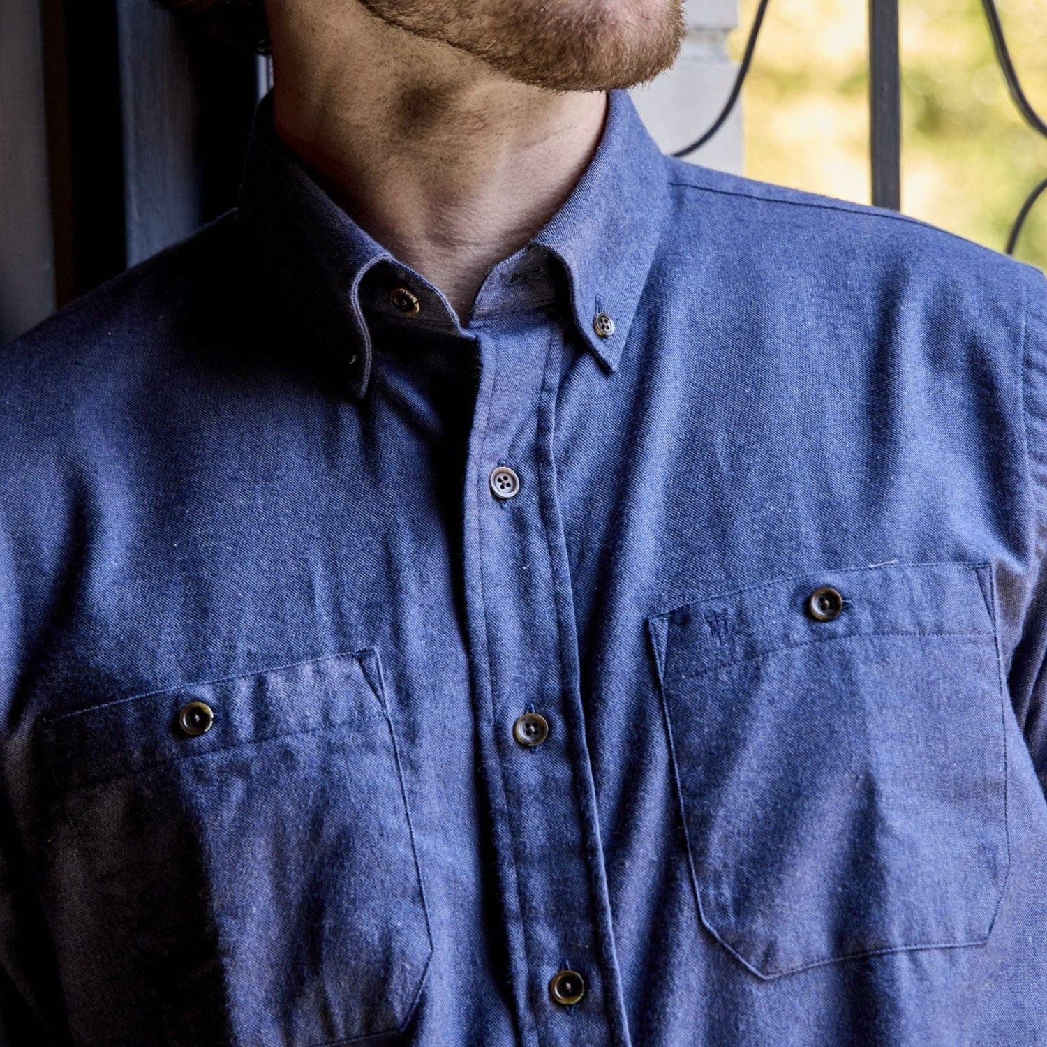 A person wears a Tom Beckbe Dixon Brushed Cotton Twill Shirt with two chest pockets, standing by a window.